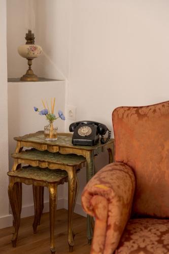 a table with a telephone and a table with a chair at Memórias Charme Residences in Covilhã