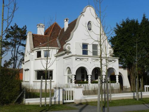 een wit huis met een rood dak bij B&B Maison Rabelais in De Haan