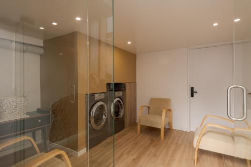 a laundry room with a washing machine and a chair at Memórias Charme Residences in Covilhã