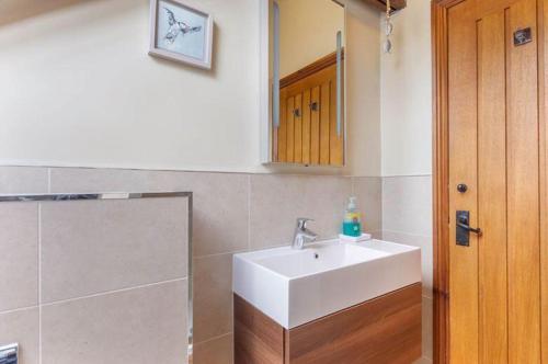 ein Badezimmer mit einem weißen Waschbecken und einem Spiegel in der Unterkunft Puffin Cottage, Bamburgh in Bamburgh