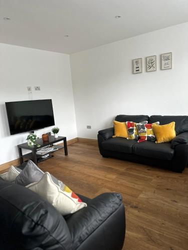 a living room with two black couches and a flat screen tv at Cornwall - The Duke and Duchess in London