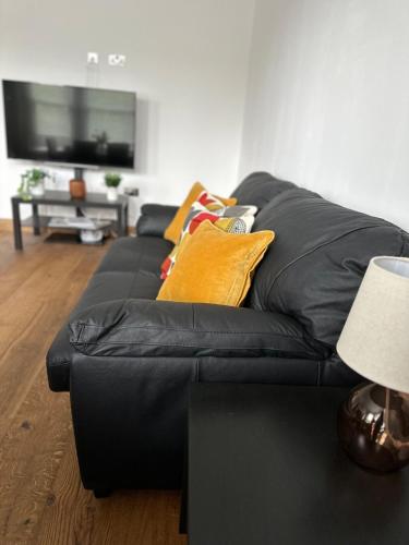 a black couch with yellow pillows in a living room at Cornwall - The Duke and Duchess in London