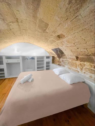 Cette chambre dispose d'un grand lit blanc et d'un mur en pierre. dans l'établissement Séjour Bordeaux, à Bordeaux