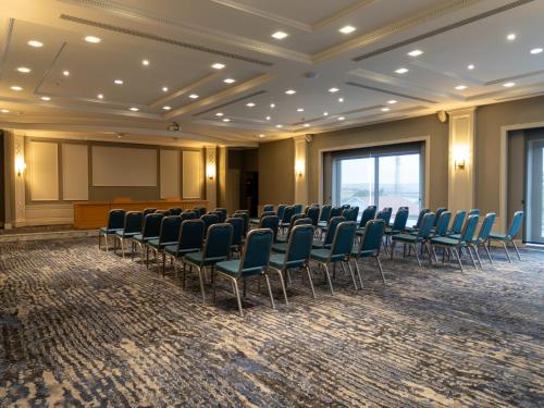 a conference room with chairs and a podium and a screen at Shirvan Grand Hotel Shamakhi in Şamaxı