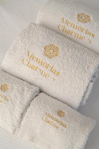 a group of white towels with gold writing on them at Memórias Charme Residences in Covilhã