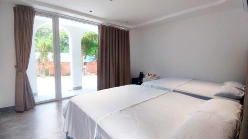 a bedroom with two beds and a large window at Moon Kê gà hotel in Phan Thiet