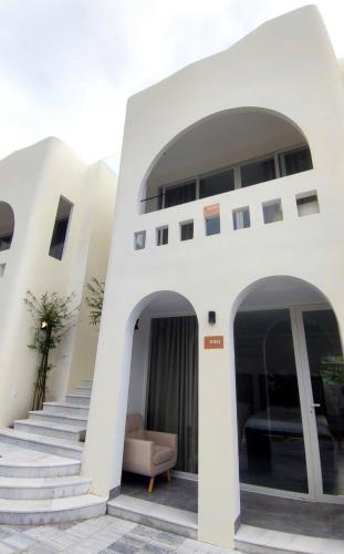 a white building with stairs and a chair in front at Moon Kê gà hotel in Phan Thiet