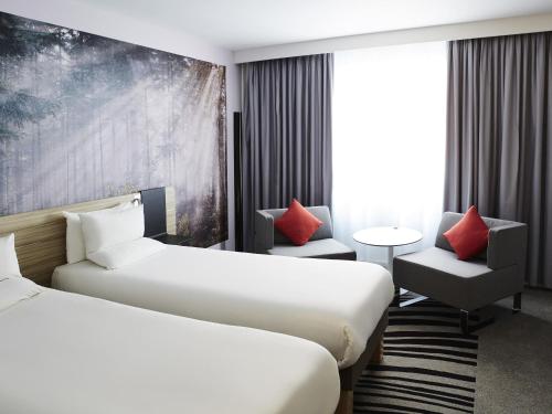 a hotel room with two beds and a chair at Novotel Manchester Centre in Manchester