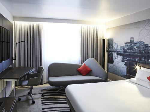 a hotel room with a bed and a couch and a desk at Novotel Manchester Centre in Manchester