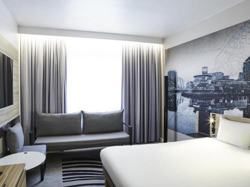 a hotel room with a bed and a couch at Novotel Manchester Centre in Manchester