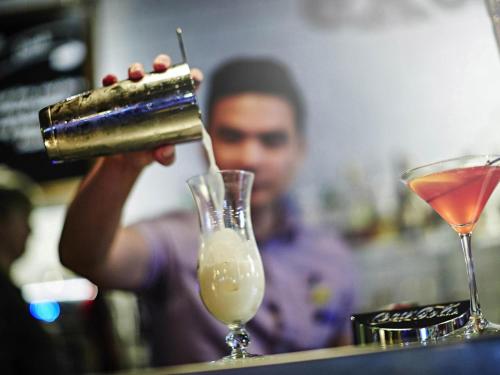 a man is making a drink at a bar at Novotel Manchester Centre in Manchester