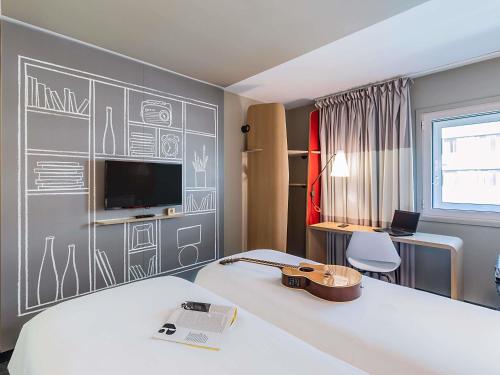 a room with a bed and a desk and a television at Hotel ibis Lisboa Liberdade in Lisbon