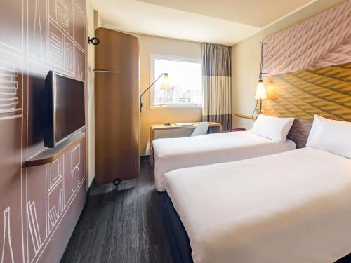 a hotel room with two beds and a flat screen tv at Hotel ibis Lisboa Liberdade in Lisbon
