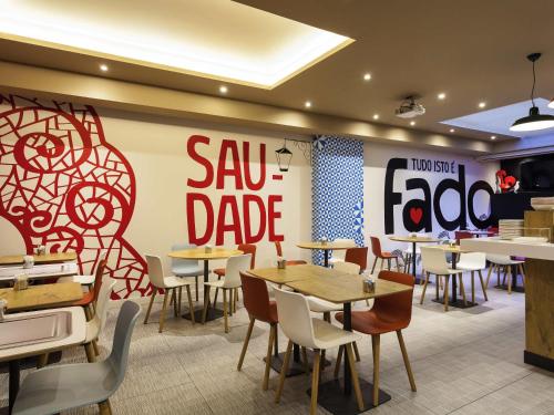 a restaurant with tables and chairs and asaw blade sign at Hotel ibis Lisboa Liberdade in Lisbon