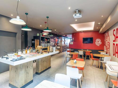 a restaurant with a counter and chairs and tables at Hotel ibis Lisboa Liberdade in Lisbon