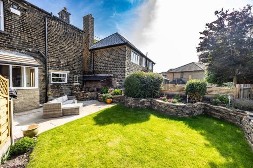 einen Hinterhof mit Rasen und Backsteinhaus in der Unterkunft Wallnook Cottage Lindley Gem in Lindley