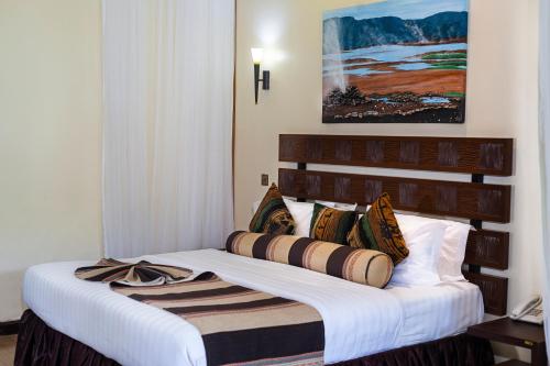 a hotel room with a bed with a white sheets and pillows at Lake Bogoria Spa Resort in Marigat
