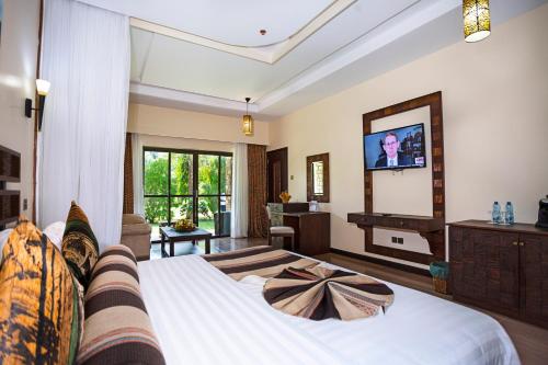 a bedroom with a large bed with a tv on the wall at Lake Bogoria Spa Resort in Marigat