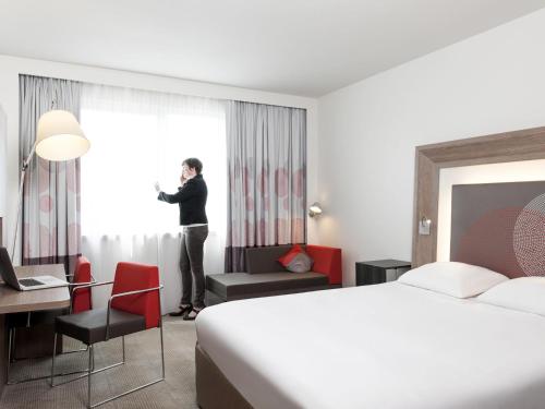 a woman standing in a hotel room with a window at Novotel Leuven Centrum in Leuven