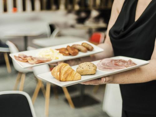 a woman is holding two plates of food at ibis Liverpool Centre Albert Dock – Liverpool One in Liverpool
