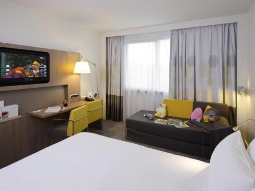 a hotel room with a bed and a tv at Novotel Leuven Centrum in Leuven