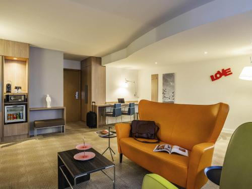 a living room with a couch and a table at Novotel Mechelen Centrum in Mechelen