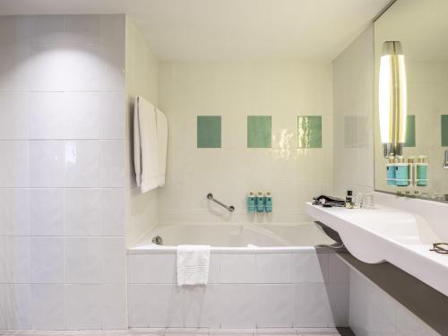 a white bathroom with a tub and a sink at Novotel Mechelen Centrum in Mechelen