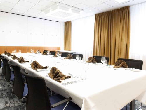a conference room with a large white table with chairs at Novotel Mechelen Centrum in Mechelen