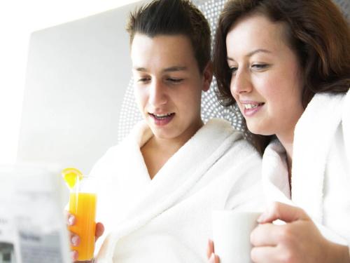 a man and a woman in a bathroom with a cup of orange juice at Novotel Mechelen Centrum in Mechelen