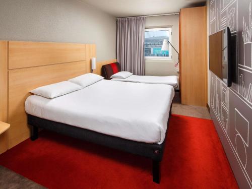 a hotel room with two beds and a television at ibis London Wembley in London