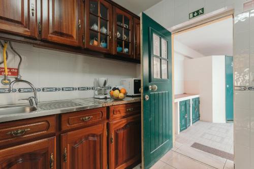 Una cocina con gabinetes de madera y una puerta verde. en Best Houses 21 - Surf House Perfect Location, en Baleal