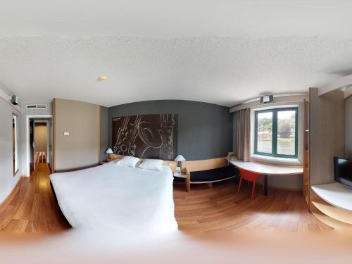 a bedroom with a white bed and a desk and a window at ibis Dinant Centre in Dinant