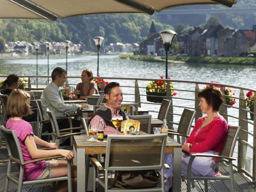 a group of people sitting at an outdoor restaurant at ibis Dinant Centre in Dinant