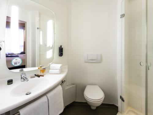 Un baño con lavabo, inodoro y espejo. en ibis Hotel Brussels Centre Gare du Midi, en Bruselas