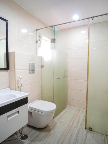 a bathroom with a toilet and a glass shower at Stay Pride Service Apartments - AC Rooms in Vijayawada - Family & Business Stays in Vijayawāda