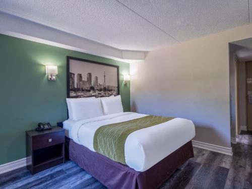 a bedroom with a large bed with a picture on the wall at Super 8 by Wyndham Toronto East ON in Toronto
