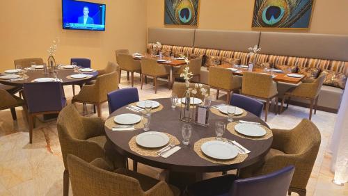 a dining room with tables and chairs and a tv at Global Hotel Panama in Panama City