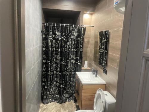 a bathroom with a black shower curtain and a sink at Номера in Dobrovelychkivka