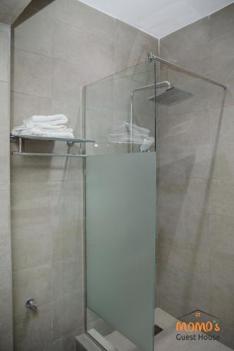 a shower with a glass door in a bathroom at Momo's Guest House in Kumasi
