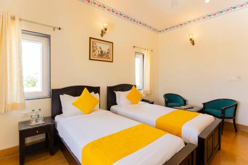 two beds in a room with yellow and white at Vasant Vilas in Udaipur
