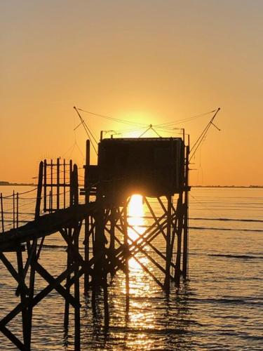 a wooden pier with the sun setting on the water at Les Volets Bleus in Bernay