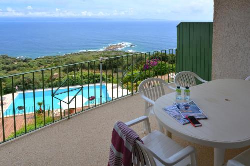 a balcony with a table and chairs and a pool at Residence Roc E Mare Cargèse in Cargèse