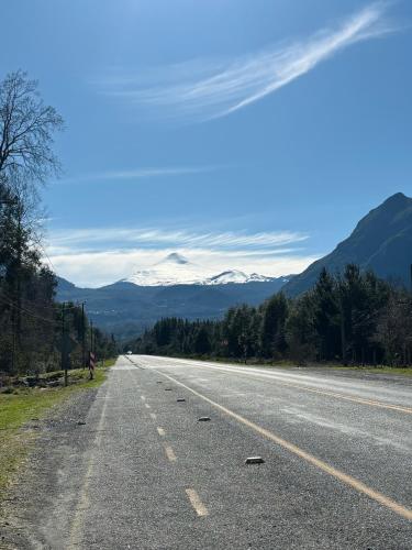 an empty road with snow capped mountains in the background at Cabañas Los Glaciares in Coñaripe