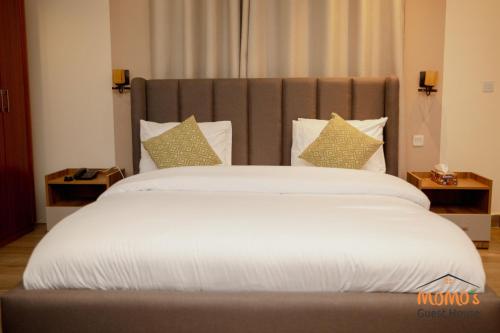 a large bed with white sheets and pillows at Momo's Guest House in Kumasi