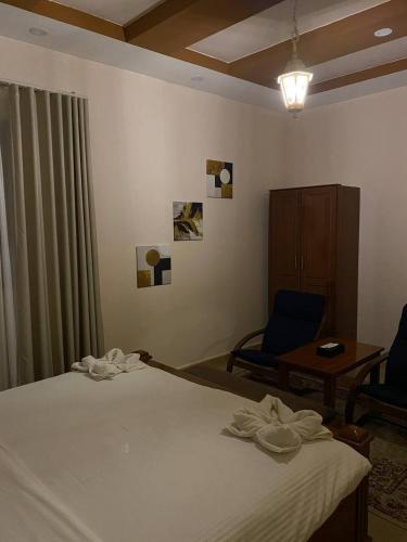 a bedroom with a bed and a chair and a table at Durrat Nizwa Inn in Nizwa