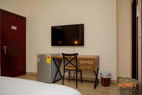 a room with a desk with a television and a chair at Momo's Guest House in Kumasi