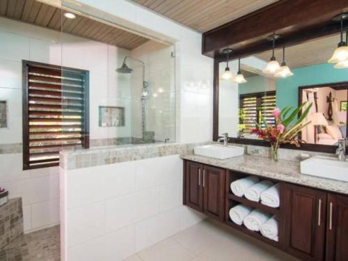 a bathroom with two sinks and a large mirror at Hospitality Expert HALF HILL Pool Beach in Montego Bay