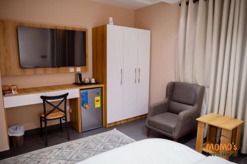 a room with a chair and a cabinet and a television at Momo's Guest House in Kumasi