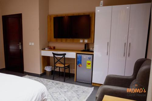 a room with a kitchen with a counter and a tv at Momo's Guest House in Kumasi