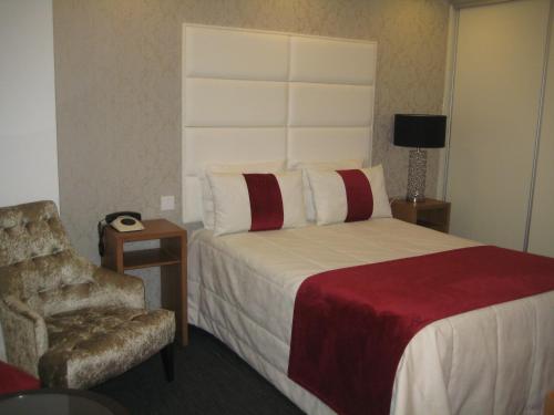 a hotel room with a bed and a chair at Josefa D`Obidos Hotel in Óbidos